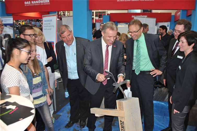  HwK-Präsident und Dachdeckermeister Kurt Krautscheid greift bei den „azubi & studientagen“ selbst zum Werkzeug, beobachtet von IHK-Präsident Manfred Sattler (links daneben) und Besuchern der Info-Veranstaltung. Fotos: HwK Koblenz