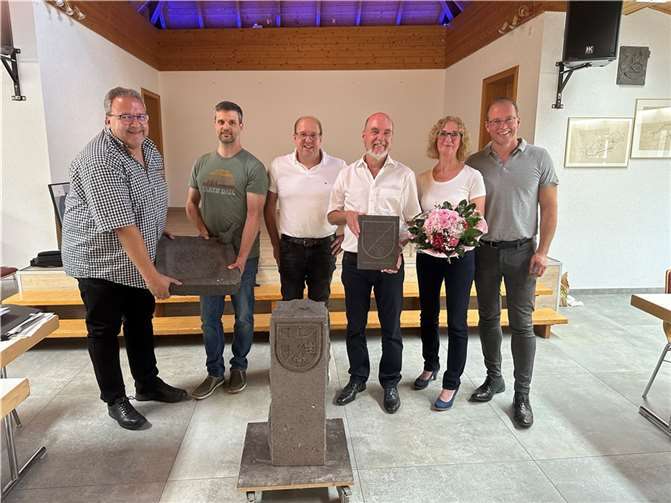 Abschiedsgeschenke und das Wappenschild der Ortsgemeinde (von links): Thomas Schmitt, Sebastian Jung, Rudolf Schüller, Rudolf und Claudia Wingender und Jörg Lempertz.