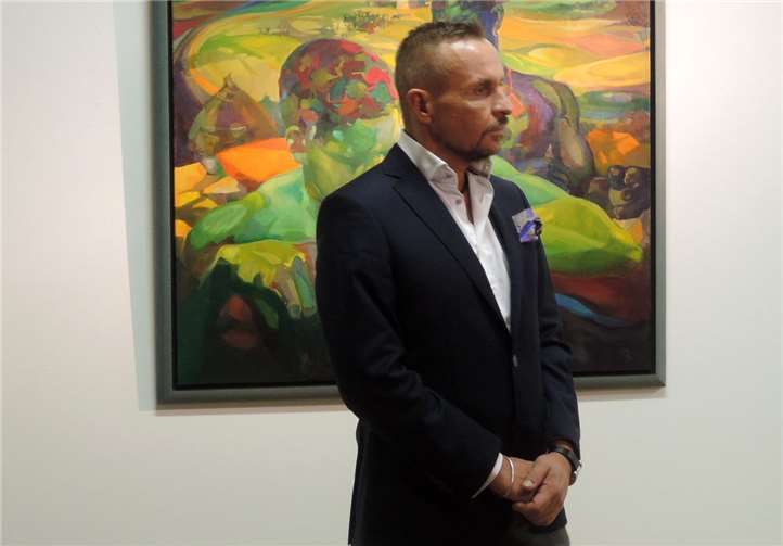 Alexander Baumgarte in der Ausstellung vor dem Gemälde seiner Mutter „A Man Without Livestock isn’t a Man“.