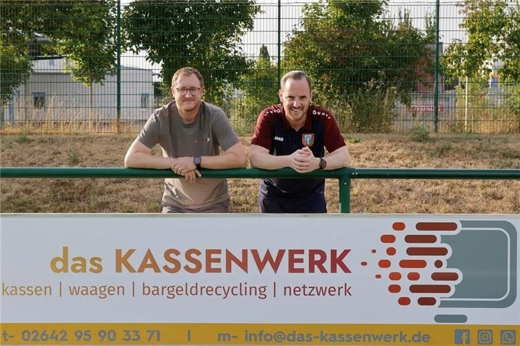 Alexander Nitzgen (das Kassenwerk) und Jan Schäfer (SV Kripp) präsentieren die neue Werbebande im Sportpark „Am Querweg“.