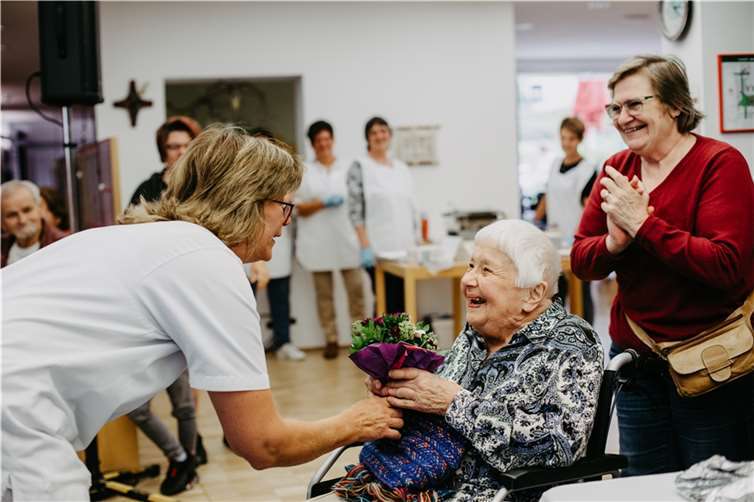 Alle machen mit bei der Stephanskirmes, und manch eine gewinnt. Mitarbeiterin Barbara Kuhn spendet das bei der Kirmes-Tombola gewonnene Blumen-Abonnement an Dorothea Schlegel aus dem vollstationären Bereich. Foto: Eduard Bretthauer