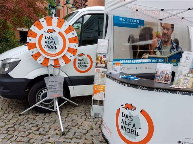 Am ALFA-Mobil-Stand informieren Mitarbeitende interessierte Bürger und Menschen mit Lese- und Schreibschwierigkeiten.  Quelle: ALFA-Mobil