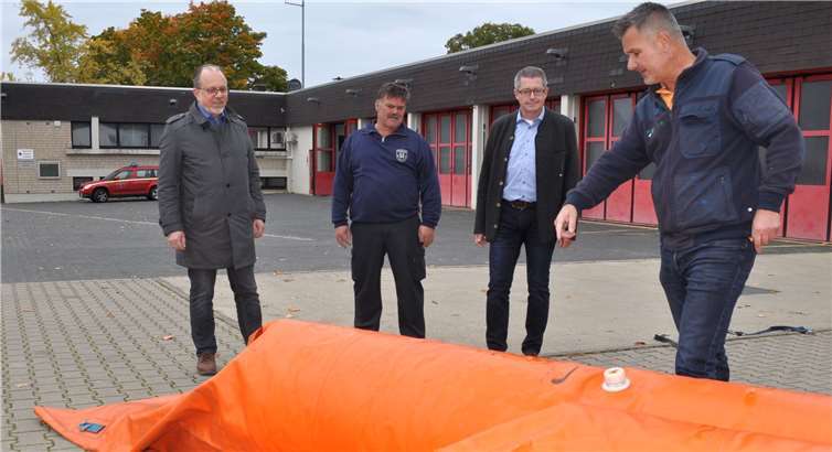 Am Feuerwehrgerätehaus veranschaulicht Andreas Roos (rechts) den Einsatz des Hochwasser-Schutzsystems. Der Technische Beigeordnete Heinz-Peter Witt, Günter Wiegershaus, Leiter der Freiwilligen Feuerwehr Meckenheim, und der Erste Beigeordnete Hans Dieter Wirtz (von links) folgen interessiert den Erläuterungen.Foto: Stadt Meckenheim