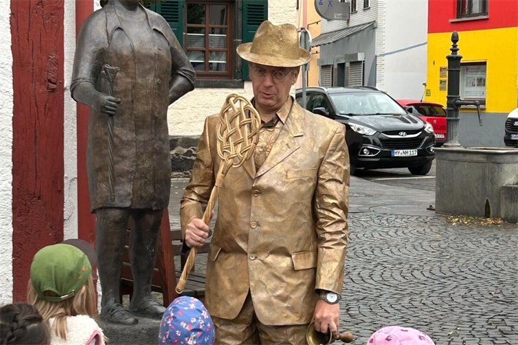 Am Kolpingplatz machten die Kinder Bekanntschaft mit der Bronzefigur von Maria Baulig. Sie erfuhren, was es mit dem Teppischklopfer und dem Ausspruch „Marie-mach-Platz“ auf sich hat.