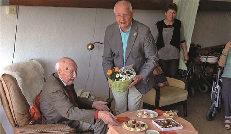 Amtmann Hans-Jochen Annuß gratuliert Emil Winheller mit einem Blumengesteck. Privat