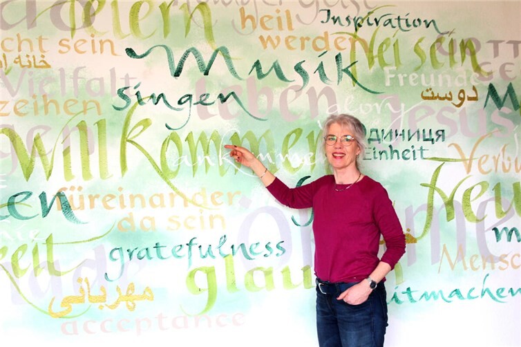 Andrea Lawrenz vor einem Ausschnitt des neuen Begrüßungsbildes.