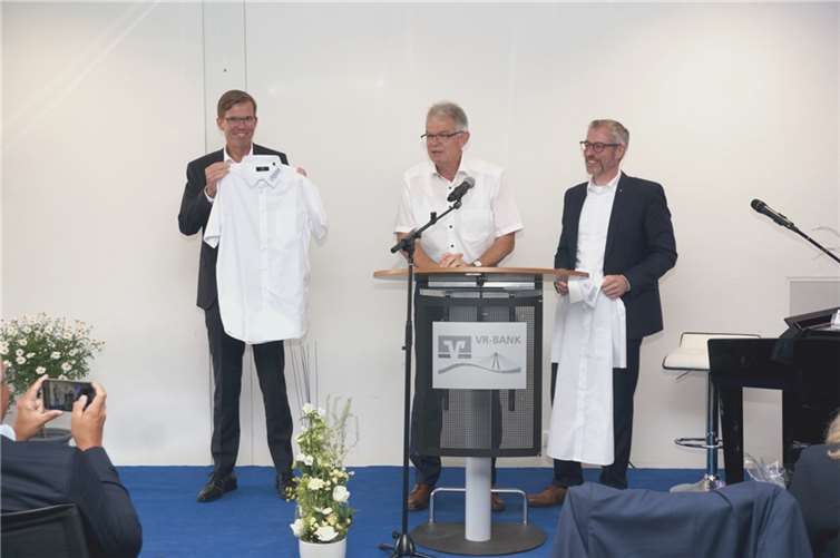 Andreas Harner, bekannt für das Tragen kurzer Hemden, überreicht seinen beiden Vorstandskollegen Michael C. Kuch (links) und Matthias Herfurth (rechts) kurzärmelige Hemden, damit sie auch zukünftig einen kühlen Kopf bewahren. Foto: VRBank