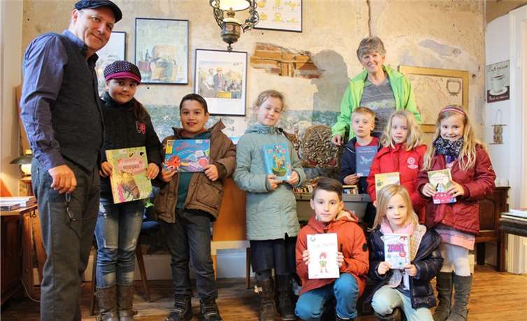 Andreas Hauffe von „Hauffes Buchsalon“ mit Rektorin Anjo Närdemann und Kindern der Klassen eins bis vier der Grundschule Remagen beim Erkunden der „Lesekoffer“.DU