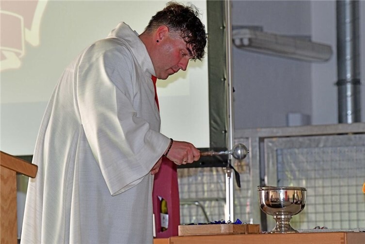 Andreas Schneider besprengt die Engel für die Feuerwehrfamilie mit Weihwasser.