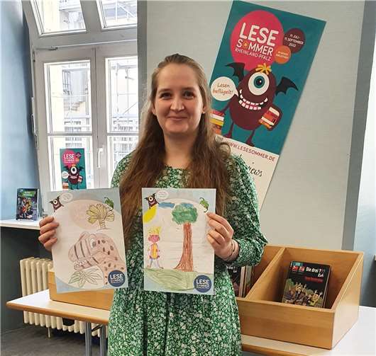 Anna Lenz vom Leitungsteam der StadtBibliothek zeigt zwei der von „Lesesommer“-Kindern erstellten Bilder. Foto: Stadt Neuwied