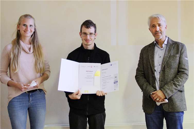 Anne-Catherine Grandmontagne und Thomas Zenner gratulieren Rene Schulz, der zugleich seine fachpraktische Fortbildung als Logistik-Praktiker (IHK) erfolgreich absolviert hat.  Foto: Caritas Werkstätten, Ulmen