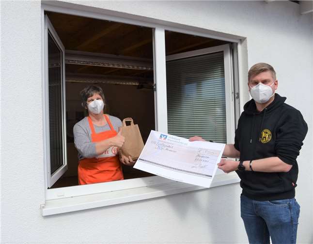 Anschaulich zeigte Angelika Schorn, wie die kontaktlose Tafelausgabe über das Tafel-Fenster in Bad Neuenahr-Ahrweiler funktioniert. Jan Treffer nutze die Gelegenheit, ihr den Scheck in Höhe von 500 Euro zu überreichen. Foto: E.T. Müller