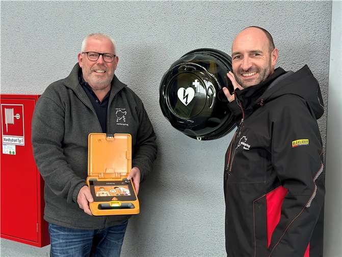 Armin Link, Leiter des Nürburgring Medical Centers (li.) und Ingo Böder, Geschäftsführer der Nürburgring 1927 GmbH & Co. KG, an einem der neu installierten, automatisierten Defibrillatoren (AED) auf dem Gelände des Nürburgrings.  Foto: Nürburgring