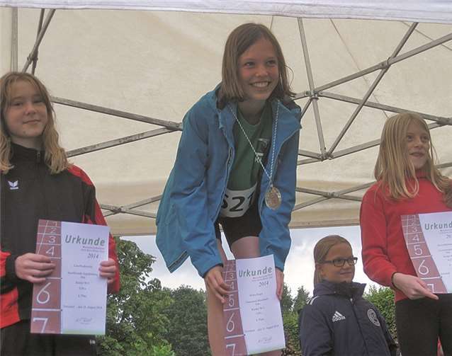 Auch der andauernde Regen bei den Kreismeisterschaften in Troisdorf konnte die gute Laune der Rheinbacher Leichtathleten nicht trüben, wie hier die dreifache Kreismeisterin Klara Engel unter dem schützenden Pavillon-Dach bei der Siegerehrung. privat