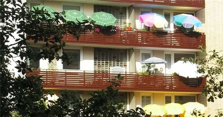 Auf dem Balkon verschafft ein geöffneter Sonnenschirm den Fensterflächen Schatten.Hermann Obermeyer