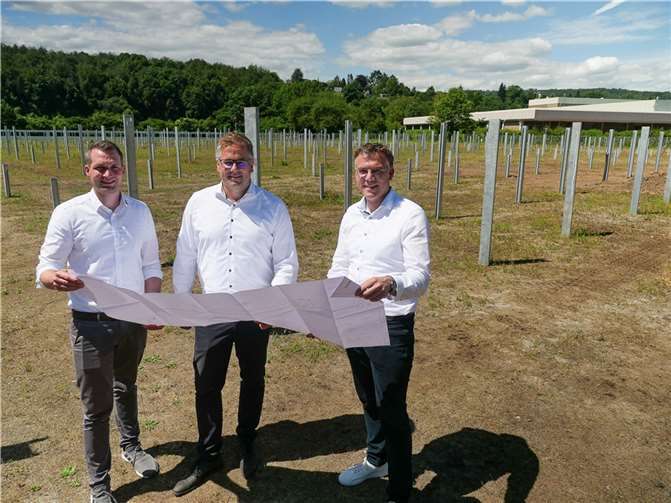 Auf dem zwei Hektar großen Areal neben der Raiffeisendruckerei entsteht der neue Solarpark. Bereichsleiter Udo Stümper sowie Thomas Kill und Julian Scherhag von der SWN Green Energy verfolgen den Aufbau. Aktuell werden die Unterkonstruktionen für die Module installiert.  Foto: SWNGE