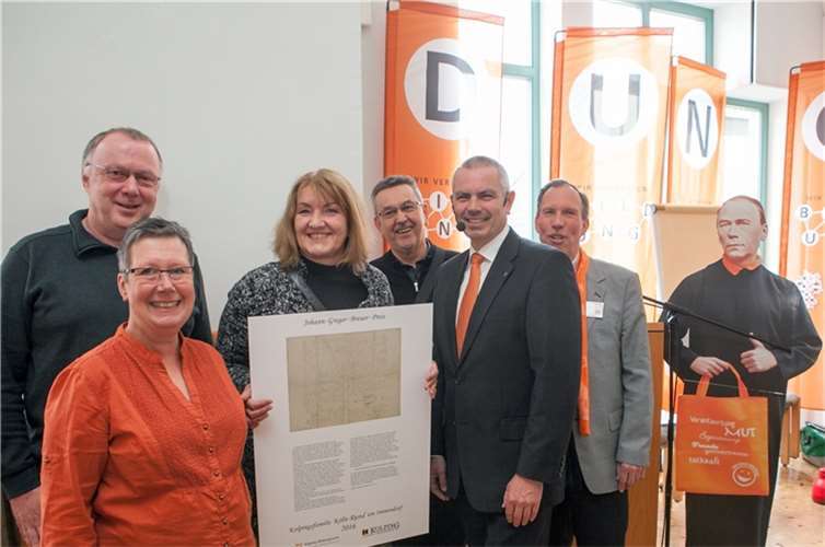 Auf der Kolping-Diözesanversammlung in Rheinbach wurde der Johann-Gregor-Breuer-Preis für innovative Bildungsarbeit an die Kolpingsfamilie Köln – Rund um Immendorf verliehen. V.l. Peter Henze (Kolpingsfamilie Köln – Rund um Immendorf), Lena Hemme, Sylvia van den Heuvel (Künstlernetzwerk „Südart“), Pfarrvikar Reinhold Steinröder, Martin Rose und Günther Herberhold vom Kolpingwerk Diözesanverband Köln. Rechts daneben ist Adolph Kolping als Pappfigur zu sehen.JOST