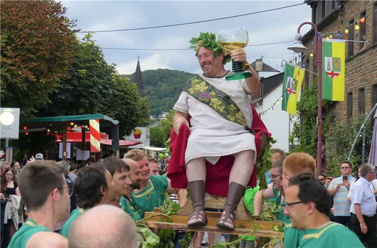 Auf einer geschmückten 12-Mann-Sänfte getragen erreichte der Weingott unter dem Beifall der Besucher den Festplatz.