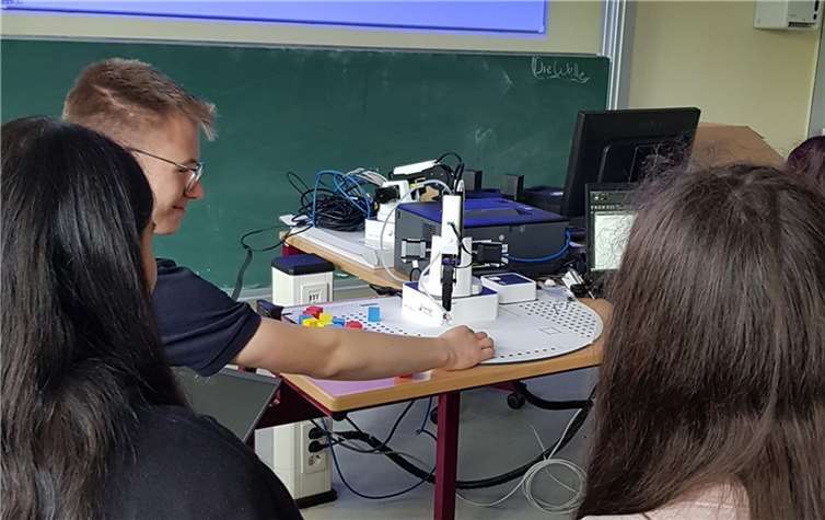 Azubis und IT-Kurs arbeiten Hand in Hand mit Roboterarmen.  Foto: Melanie Thönnes
