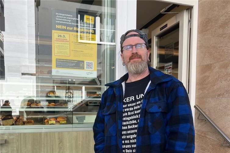 Bäcker Dominik Christian vor seiner Bäckerei mit einem Plakat der Bürgerinitiative „Zurück zur ursprünglichen Verkehrsführung in Oberlahnstein“. Foto: „Zurück zur ursprünglichen Verkehrsführung“ in Oberlahnstein“