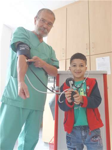 Behzad „misst“ bei Dr. Matthias Bausch Blutdruck.