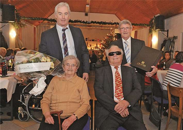 Bei der Adventsfeier in Holzweiler erhielten die ältesten Teilnehmer, Helene Porz aus Vettelhoven und Josef Schmidt aus Holzweiler, aus der Hand der beiden Ortsvorsteher Stefan Wuzèl und Bruno Zimmermann Blumen und Wein. VJ