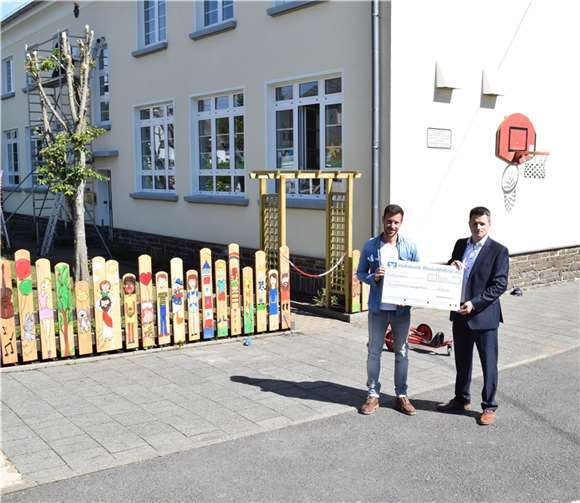 Bei der symbolischen Scheckübergabe vor dem erneuerten Holzzaun (v.l): Stefan Buhr, Schulleiter der Grundschule Langenfeld und Christian Weiß, Filialleiter der Geschäftsstelle Mayen.  Foto: Volksbank RheinAhrEifel eG