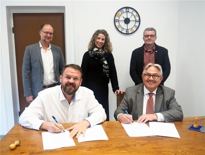 Bendorfs Bürgermeister Christoph Mohr (links) und der Bürgermeister der Verbandsgemeinde Vallendar, Adolf T. Schneider, besiegeln mit ihrer Unterschrift die neue Zweckvereinbarung. Im Hintergrund (v. l.): Thomas Bach, Fachbereichsleiter Ordnung und Soziales Stadt Bendorf, Nadine De Bock, Geschäftsführerin der vhs Bendorf, und Dirk Knopp, Leitung Fachbereich Bürgerdienste VG Vallendar. Foto: Stadt Bendorf