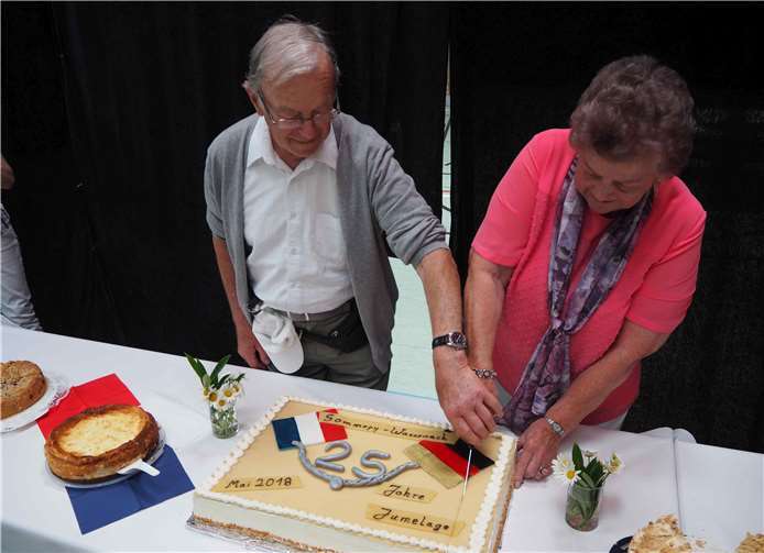 Bernard Soudant, Ortsbürgermeister Sommepy zum Zeitpunkt derVertragsunterzeichnung, und Agnes Müller, Witwe von Werner Müller,schneiden gemeinsam die Festtagstorte an.