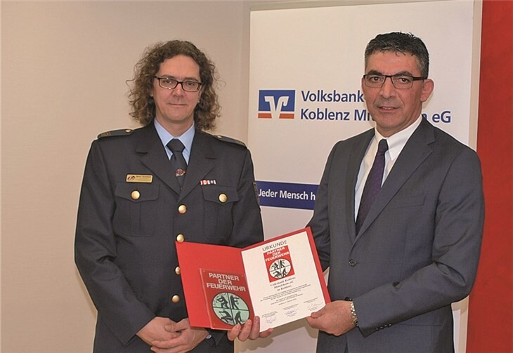 Bernd Naunheim (l.), Vizepräsident des Landesfeuerwehrverbandes, überreicht die Urkunde und die Ehrenplakette „Partner der Feuerwehr“ an Walter Müller, Vorstand der Volksbank Koblenz Mittelrhein.US