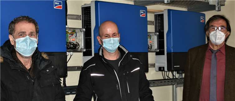 Berthold Junglas, Tore Füll und Bürgermeister Klaus Bell vor den drei Wechselrichtern, die in einer Garage des Verwaltungsgebäudes installiert wurden und den Gleichstrom der Solarmodule in Wechselstrom zur Einspeisung ins öffentliche Stromnetz umwandeln.