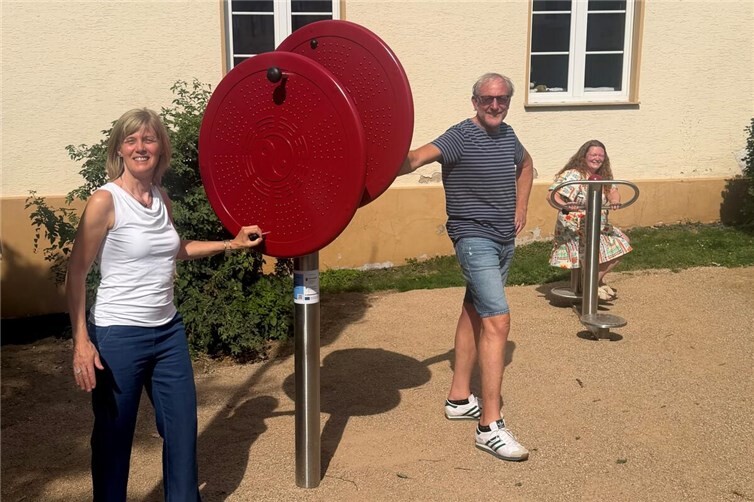 Bewegungsleiterin Lisa Hütter-Klemmer, Ortsvorsteher Olaf Wulf und Lisa Althoff von der Stadt Remagen (v.l.n.r.) freuen sich über die neuen Outdoor-Fitnessgeräte am Dorfmitteplatz.
