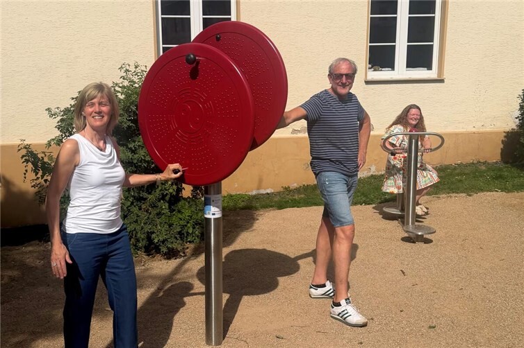 Bewegungsleiterin Lisa Hütter-Klemmer, Ortsvorsteher Olaf Wulf und Lisa Althoff von der Stadt Remagen (v.l.n.r.) freuen sich über die neuen Outdoor-Fitnessgeräte am Dorfmitteplatz.