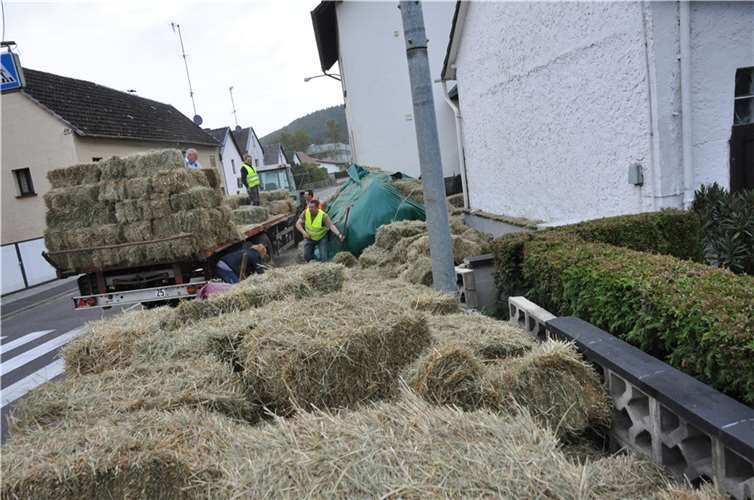 Traktor mit Heuballen kippt um 
