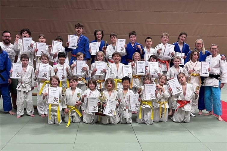 Bildunterschrift: Großer Jubel beim JC Neuwied: Beim Bärchen-Pokal in Limburg belegte der Nachwuchs des Vereins mit 31 Starterinnen und Startern den dritten Platz in der Vereinswertung und wurde damit bester Verein aus Rheinland-Pfalz. Den Pokal präsentieren stolz die jüngsten Teammitglieder Jule Karbach und Emil Krämer, flankiert von ihren Trainern und der erfolgreichen Mannschaft.