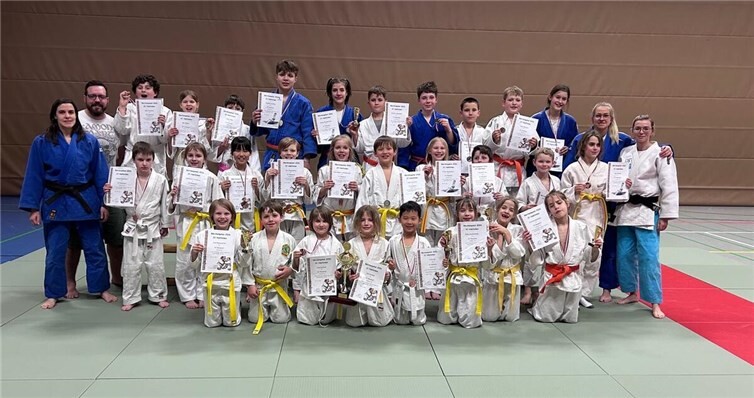 Bildunterschrift: Großer Jubel beim JC Neuwied: Beim Bärchen-Pokal in Limburg belegte der Nachwuchs des Vereins mit 31 Starterinnen und Startern den dritten Platz in der Vereinswertung und wurde damit bester Verein aus Rheinland-Pfalz. Den Pokal präsentieren stolz die jüngsten Teammitglieder Jule Karbach und Emil Krämer, flankiert von ihren Trainern und der erfolgreichen Mannschaft.