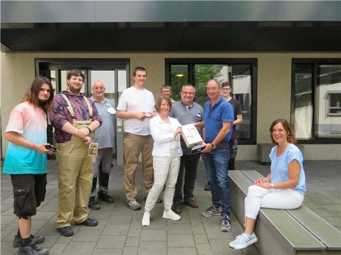Birgit Heider-Neideck, Leitung Medizinisch-berufliche Rehabilitation (MBR), übergibt in Anwesenheit von Mitarbeitern und Rehabilitanden der MBR sowie Dr. Guido Ketter, Ärztlicher Direktor der BDH-Klinik Vallendar, die von den Rehabilitanden hergestellte Lampe an Ralf Stockschläder, Inhaber der Jakob Stockschläder GmbH und Co. KG. Foto: BDH-Zentrum Vallendar