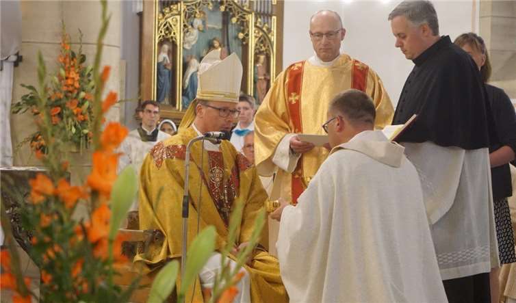 Bischof Ackermann überreicht dem Neupriester nach seiner Einkleidung Hostien und Kelch für seine erste Eucharistie.