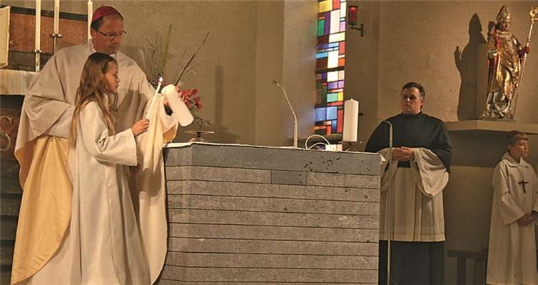 Bischof Ackermann und eine Messdienerin entzünden die erste Kerze auf dem geweihten Altar. privat