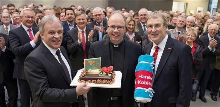 Bischof Stephan Ackermann erhält von Kurt Krautscheid (l.) und Hauptgeschäftsführer Alexander Baden (r.) eine Torte mit dem Slogan der Imagekampagne des Handwerks „Am Anfang waren Himmel und Erde. Den ganzen Rest haben wir gemacht.“ Foto: Herbert Piel / P!ELmedia