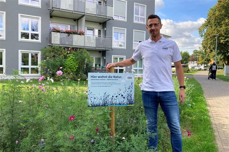 Björn Müller, bei der GSG für die Außenflächen verantwortlich, vor blühenden Biodiversitätsflächen am Zeppelinhof. 