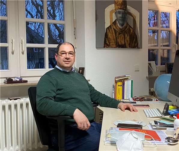 Björn Schacknies in seinem Büro als Hausrektor in Vallendar. Hinter ihm ein modernes Gemälde, das Papst Benedikt XVI. zeigt. Foto: Pallottiner