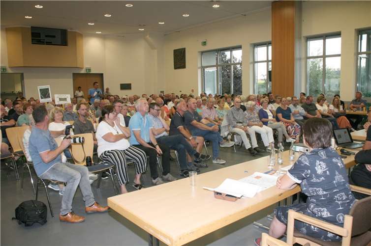 Blick in das voll besetzte Bürgerhaus Hausen. Mitglieder der Bürgerinitiative BIMO drückten ihren Unmut über das Projekt auf Transparenten aus.
