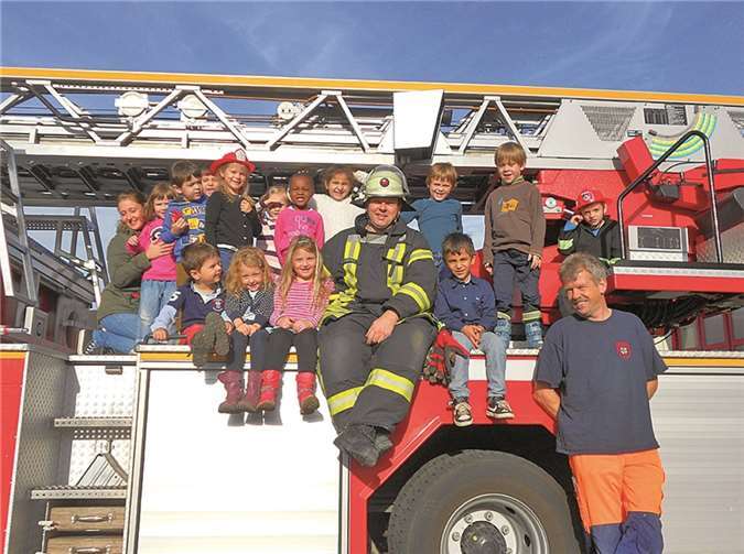 Brandschutzerziehung mit Spaß: Die Kinder der Kita „Rappelkiste“ auf einem großen Feuerwehrauto mit Feuerwehrmann Oliver Fischer (Mitte) und Christoph Rehn. Stadt Meckenheim