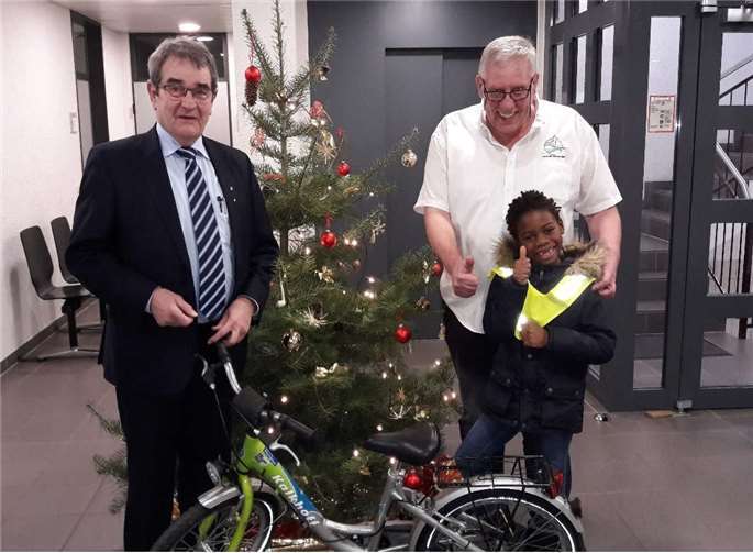 Bürgermeister Helmut Probst, Wolfgang Behrens von der Kreisverkehrswacht und Kevin Emmanuel Kargbo bei der vorweihnachtlichen Bescherung.privat