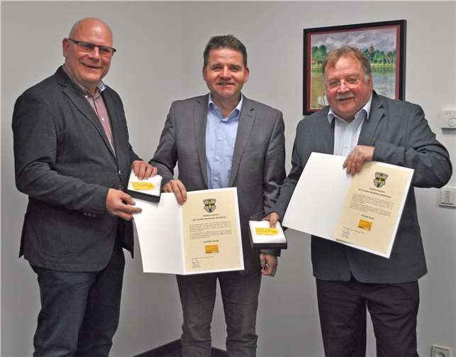 Bürgermeister Holger Jung (Mitte) übergibt die Jubiläums-Ehrenamtskarten samt Urkunden an Joachim Clever (links) und Friedel Groß (rechts). Foto: Stadt Meckenheim