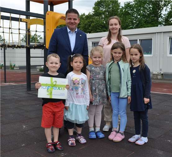 Bürgermeister Holger Jung (hinten links) übergibt einen Methodenkoffer an die Zusatzgruppe „Neue Mitte“ mit ihrer stellvertretenden Leitung Daniela Kopschetzky (hinten rechts). Quelle: Stadt Meckenheim