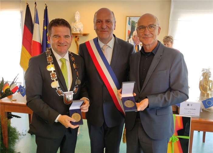 Bürgermeister Holger Jung (links) und sein Amtsvorgänger Bert Spilles (rechts) nehmen die Ehrenplakette der Stadt Le Mée-sur-Seine von Bürgermeister Franck Vernin (Mitte) entgegen. Foto: Bernd Rafflenbeul