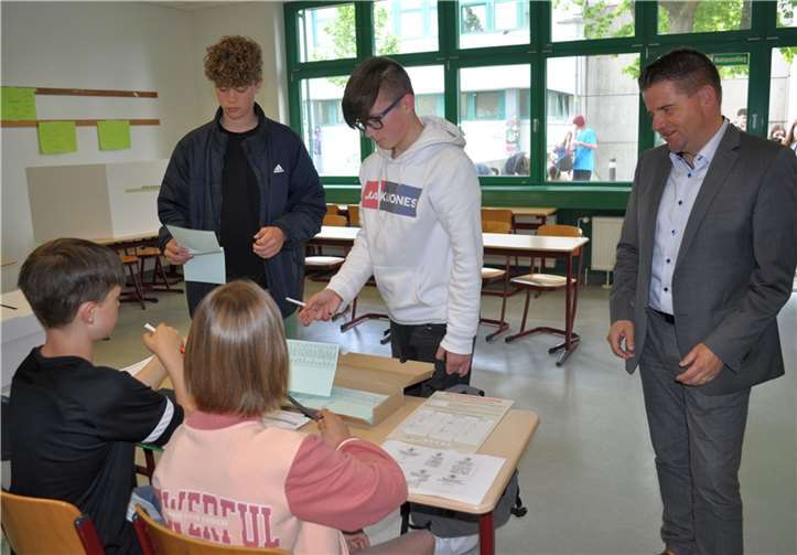 Bürgermeister Holger Jung (rechts) beobachtet die Ausgabe des Stimmzettels durch den Wahlvorstand an die jungen Wählenden. Foto: Stadt Meckenheim