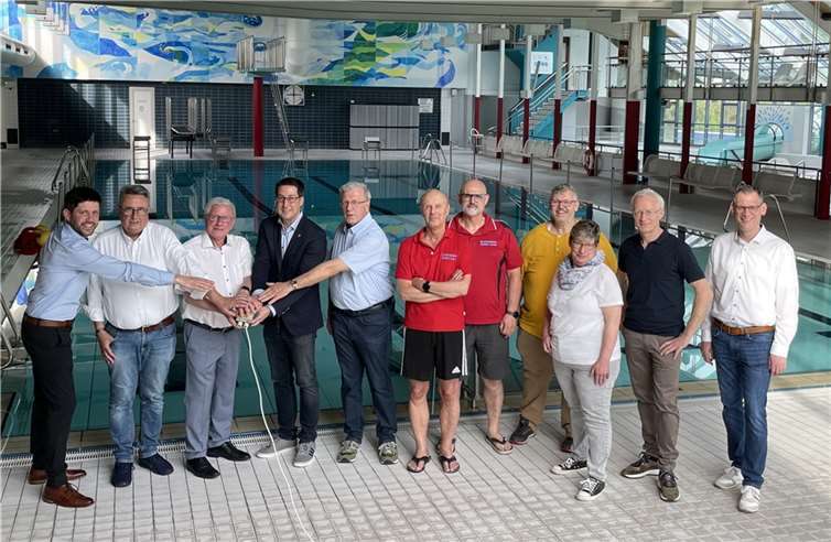 Bürgermeister Jürgen Hoffmann (FDP), die Beigeordneten Alois Hansen (CDU) und Hans-Peter Döpgen (FWG) sowie die Fraktionsvorsitzenden Christian Simon (SPD) und Matthias Müller (FWG), Büroleiter Andreas Schorn, Bauamtsleiter Martin Steinmetz und Mitarbeiterinnen und Mitarbeiter des Freizeitbades drücken symbolisch den „AUS“-Schalter. Quelle: VG Zell